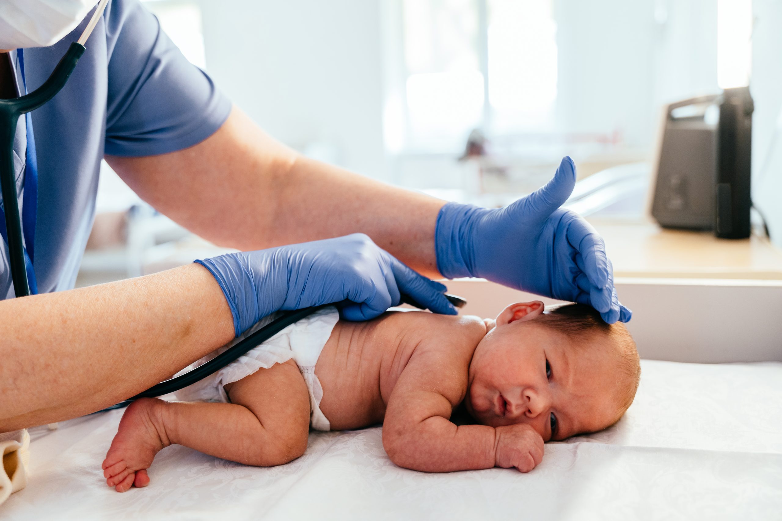 Nurse examining newborn baby back with stethoscope